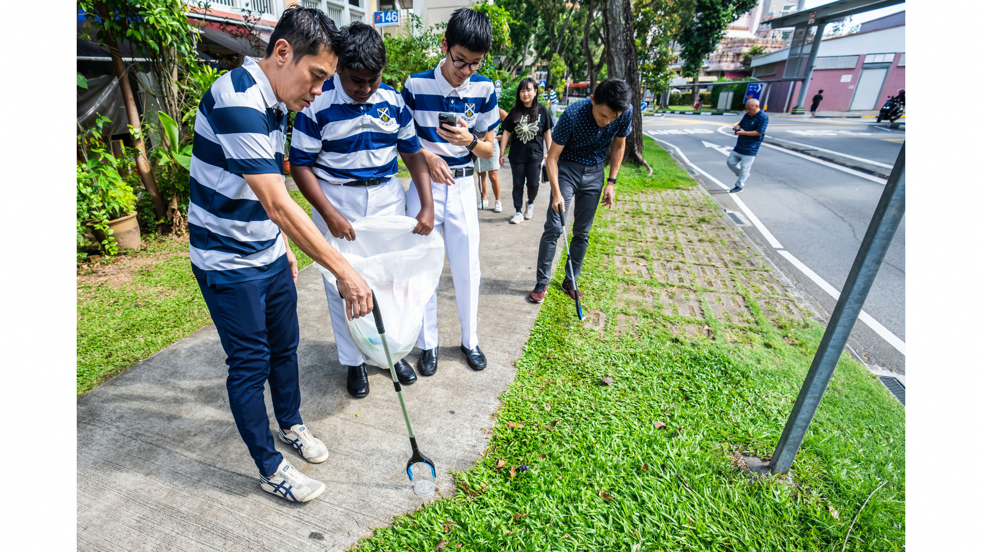 students, SPS Baey, and Mr Lee Han Hwa, Principal, picking up litter along the roads