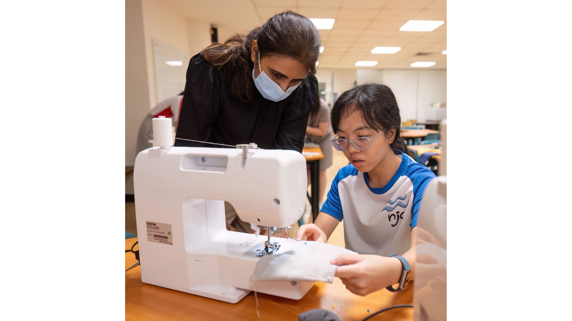 Zinobia (left) guiding a NJC student with crafting the pouch.